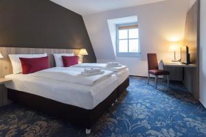 Una habitación de hotel con una cama grande con almohadas rojas. en martas Hotel Lutherstadt Wittenberg, en Lutherstadt Wittenberg