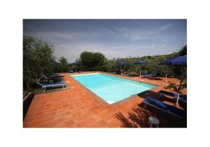 a large swimming pool with blue chairs and umbrellas at Agriturismo Molinuzzo in Barberino di Val dʼElsa