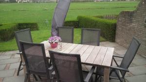 een houten tafel en stoelen met bloemen op een patio bij Uut in Thuus 21A in Buren