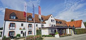 un grand bâtiment blanc avec drapeaux devant lui dans l'établissement Hotel Hirsch, à Neu-Ulm