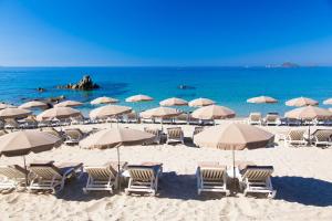 a beach with chairs and umbrellas and the ocean at Hôtel Le Week end in Ajaccio