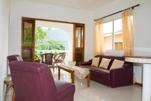 a living room with purple furniture and a fireplace at Josies Cottage in Beau Vallon