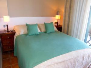 a bedroom with a bed with green sheets and pillows at Lirio in L'Ampolla