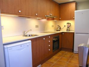a kitchen with wooden cabinets and a sink and a refrigerator at Lirio in L'Ampolla