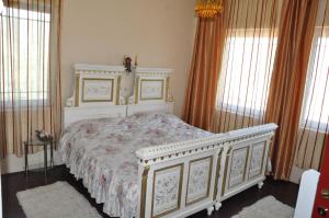 a bedroom with a white bed with a floral bedspread at Vila Kraljica in Vrdnik