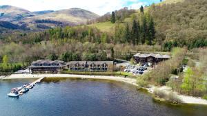an aerial view of a resort with a boat in the water at The Lodge On Loch Lomond Hotel in Luss