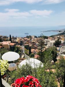 Blick auf eine Stadt von einem Hügel mit Blumen in der Unterkunft Villa Greta Hotel Rooms & Suites in Taormina