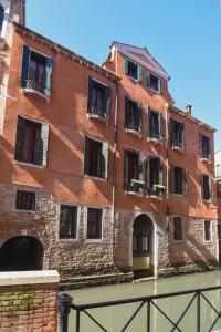 a red brick building with windows on a canal at Palazzetto San Lio, Rialto in Venice
