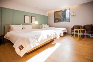 um quarto de hotel com duas camas e um sofá em Seomyeon Brown-dot hotel Gold em Busan