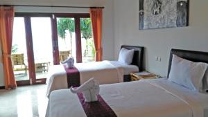 a hotel room with two beds with a cross on them at Starsand Beach Resort in Sekotong
