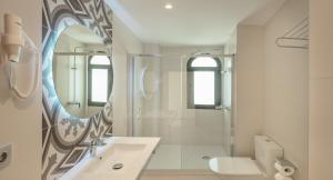 Baño blanco con lavabo y espejo en Gastrohotel Boutique RH Canfali, en Benidorm