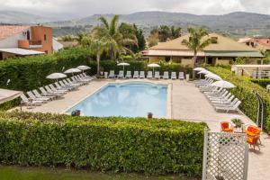 a swimming pool with chairs and umbrellas at Case Vacanze Paradise Beach Vicino Cefalù PISCINA APERTA in Campofelice di Roccella