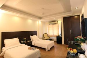 Habitación de hotel con 2 camas y escritorio en The Legend Inn Delhi, en Nueva Delhi