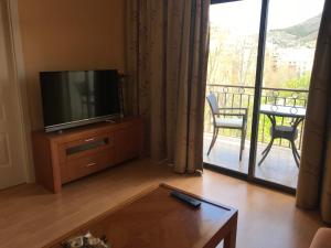 Una sala de estar con televisión y balcón. en Hotel Alfonso VIII De Cuenca, en Cuenca
