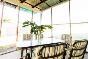 una sala da pranzo con tavolo, sedie e una pianta di Coal d' Vine Cottage - Cessnock NSW a Cessnock
