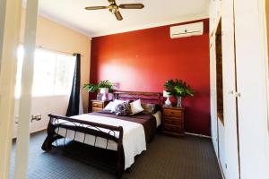 a bedroom with a red accent wall and a bed at Coal d' Vine Cottage - Cessnock NSW in Cessnock