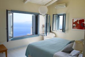 - une chambre avec un lit et une grande fenêtre dans l'établissement Urania Luxury Villas, à Vasiliki