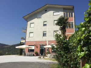 ein großes Gebäude mit Tischen und Sonnenschirmen davor in der Unterkunft Albergo Ristorante La Greppia in Montedivalli Chiesa