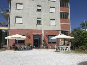 two tables and umbrellas in front of a building at Albergo Ristorante La Greppia in Montedivalli Chiesa
