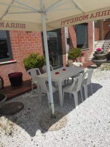einen weißen Tisch und Stühle unter einem Schirm in der Unterkunft Albergo Ristorante La Greppia in Montedivalli Chiesa
