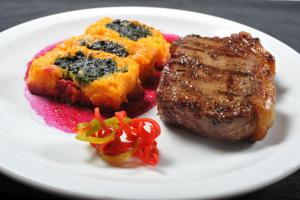 a white plate with a steak and a piece of food at Hotel de la Cañada in Córdoba