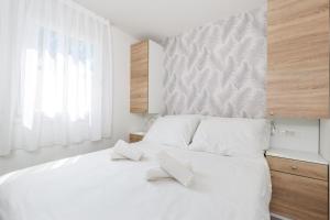 a bedroom with a white bed with two pillows on it at Mini camping FUNTANA in Poreč