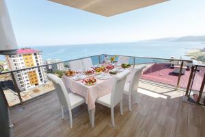 a dining table with white chairs and a view of the ocean at North Pearl Residence in Trabzon