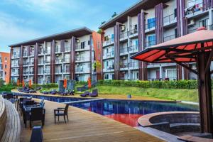 a hotel with a swimming pool with chairs and an umbrella at Studio Condo in Replay E305 - across the road from Bangrak Beach SDV210-By Samui Dream Villas in Bangrak Beach
