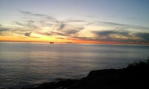 a sunset over the ocean with a boat in the water at La Casa di Ulisse B&B in Quercianella