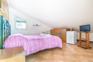ein Schlafzimmer mit einem Bett mit einer lila Decke in der Unterkunft Paradise Beach camera mansardata vicino Cefalù PISCINA APERTA in Campofelice di Roccella