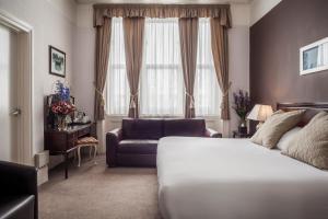 a bedroom with a bed and a couch and a window at OYO Devonshire Park Hotel in Eastbourne