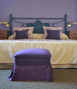 a bed with a purple ottoman in front of it at Hotel de la Cañada in Córdoba
