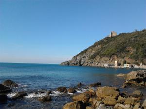 a rocky beach with a lighthouse on top of a hill at La Casa di Ulisse B&B in Quercianella