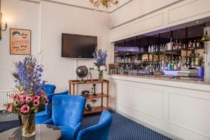a bar with blue chairs and a counter at OYO Devonshire Park Hotel in Eastbourne