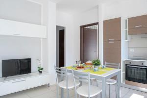 a white kitchen with a table and chairs and a tv at Green Residence in Rimini