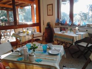 a dining room with tables and chairs and windows at La Casa di Ulisse B&B in Quercianella