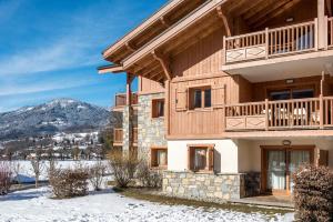 un gran edificio con balcón y montañas en el fondo en CGH Résidences & Spas La Reine des Prés, en Samoëns