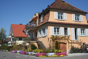 a yellow house with white windows and flowers on the street at Villa Linke am Bodensee in Nonnenhorn