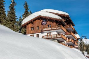 un edificio sobre una ladera nevada con nieve en CGH Résidences & Spas Chalet Les Marmottons, en La Rosière