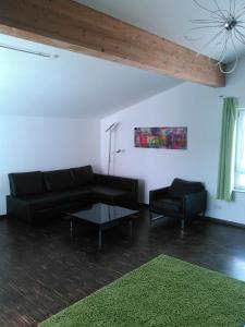 a living room with a black couch and a chair at Ferienwohnung zum Kletterturm in Kaufbeuren