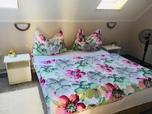 1 cama con edredón y almohadas de flores en Judit Apartments, en Hévíz