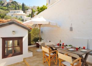 a patio with a table and chairs and an umbrella at Hydra Optima in Hydra