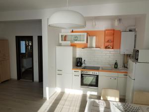 a kitchen with white appliances and orange cabinets at Biandada Apartments in Mamaia Sat/Năvodari