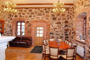 uma sala de jantar com uma mesa e uma parede de pedra em Vecgulbenes muiža em Gulbene