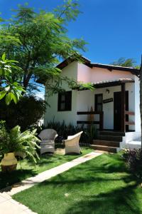 a small white house with a grass yard at Hotel e Pousada La Dolce Vita in Canoa Quebrada