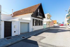 a white house with a garage on a street at The Beach House in Praia da Barra