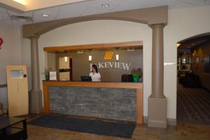 a woman standing at a reception counter in a lobby at Lakeview Inns & Suites - Fort Saskatchewan in Fort Saskatchewan