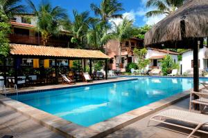 a swimming pool at a resort with chairs and palm trees at Hotel e Pousada La Dolce Vita in Canoa Quebrada