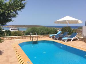 a swimming pool with two chairs and an umbrella at Kythira Golden Resort in Diakofti