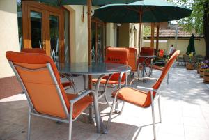 a table and chairs with an umbrella on a patio at Hotel Flóra** in Orosháza